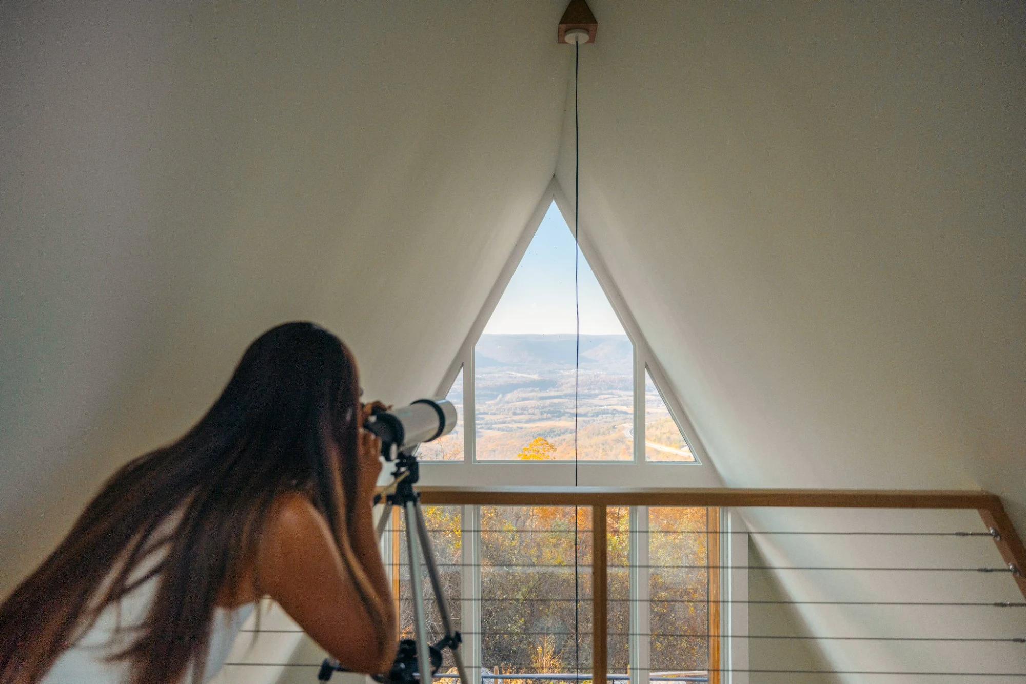 Brass telescope positioned at the triangular peak window for stargazing at The A-Frame luxury Tennessee retreat