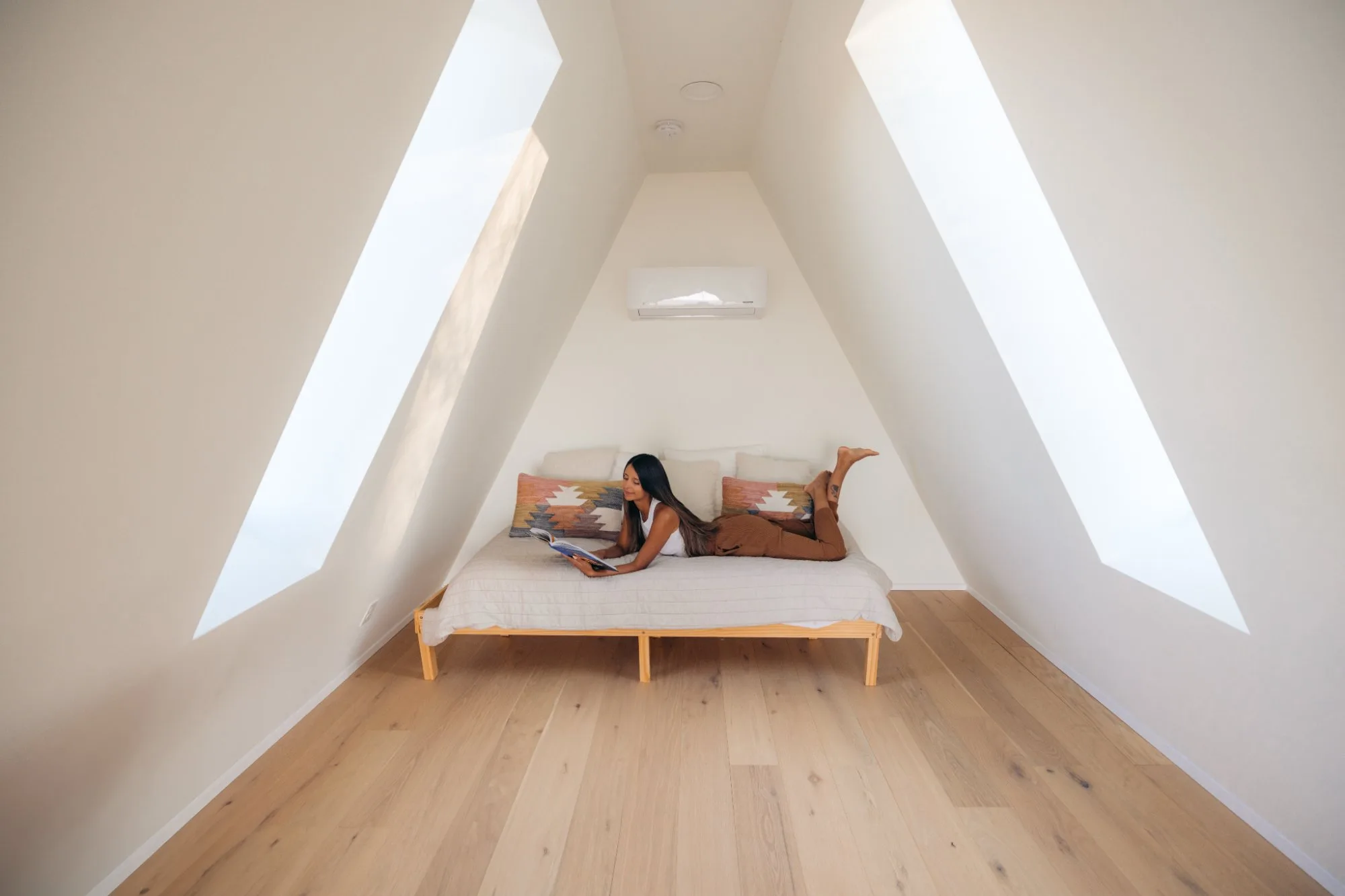 Woman reading in the third-floor loft with triangular windows at The A-Frame Tennessee