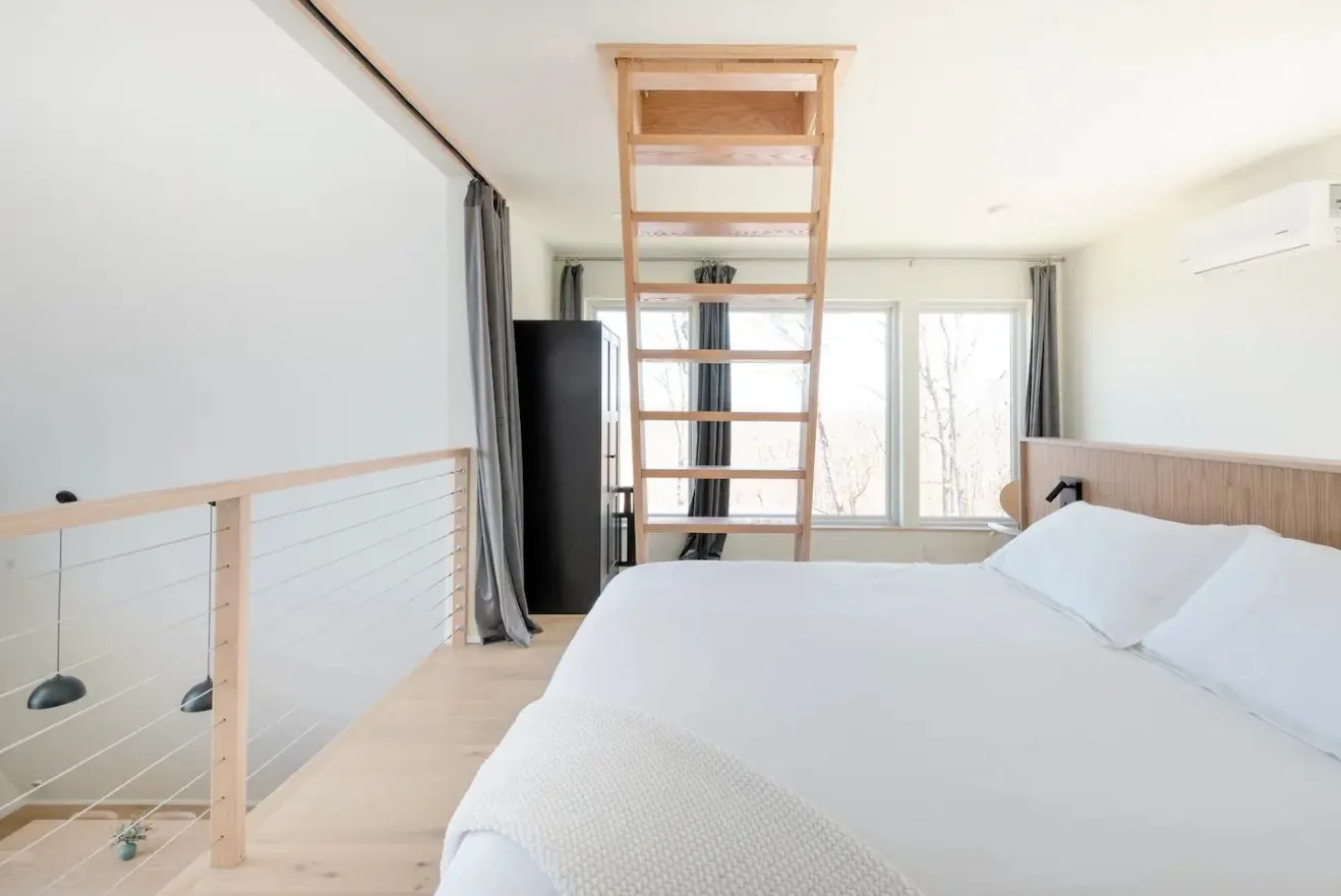 Primary bedroom with oak headboard and ship ladder to loft at The A-Frame Tennessee