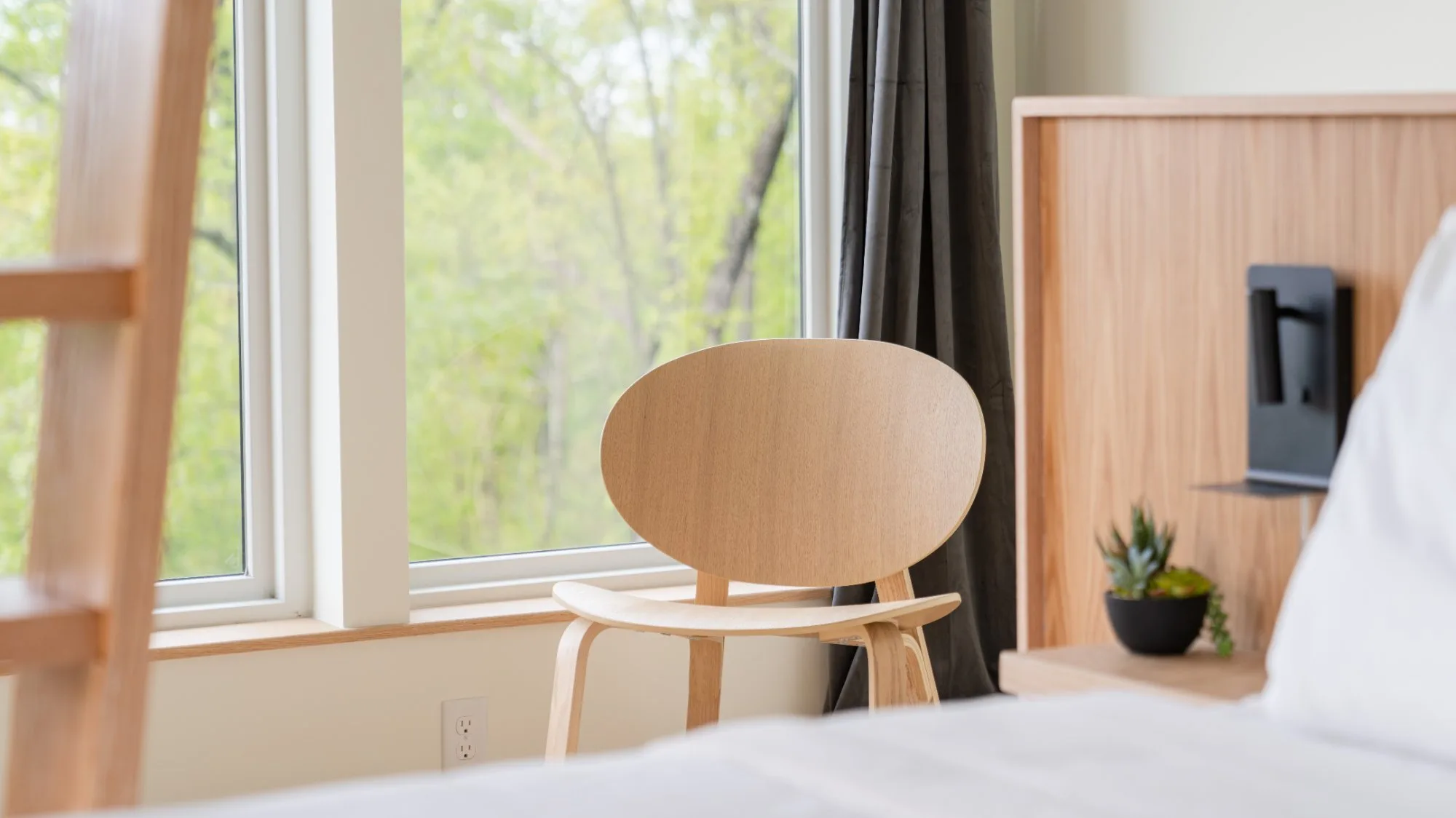 Mid-century chair and oak headboard detail in primary bedroom at The A-Frame