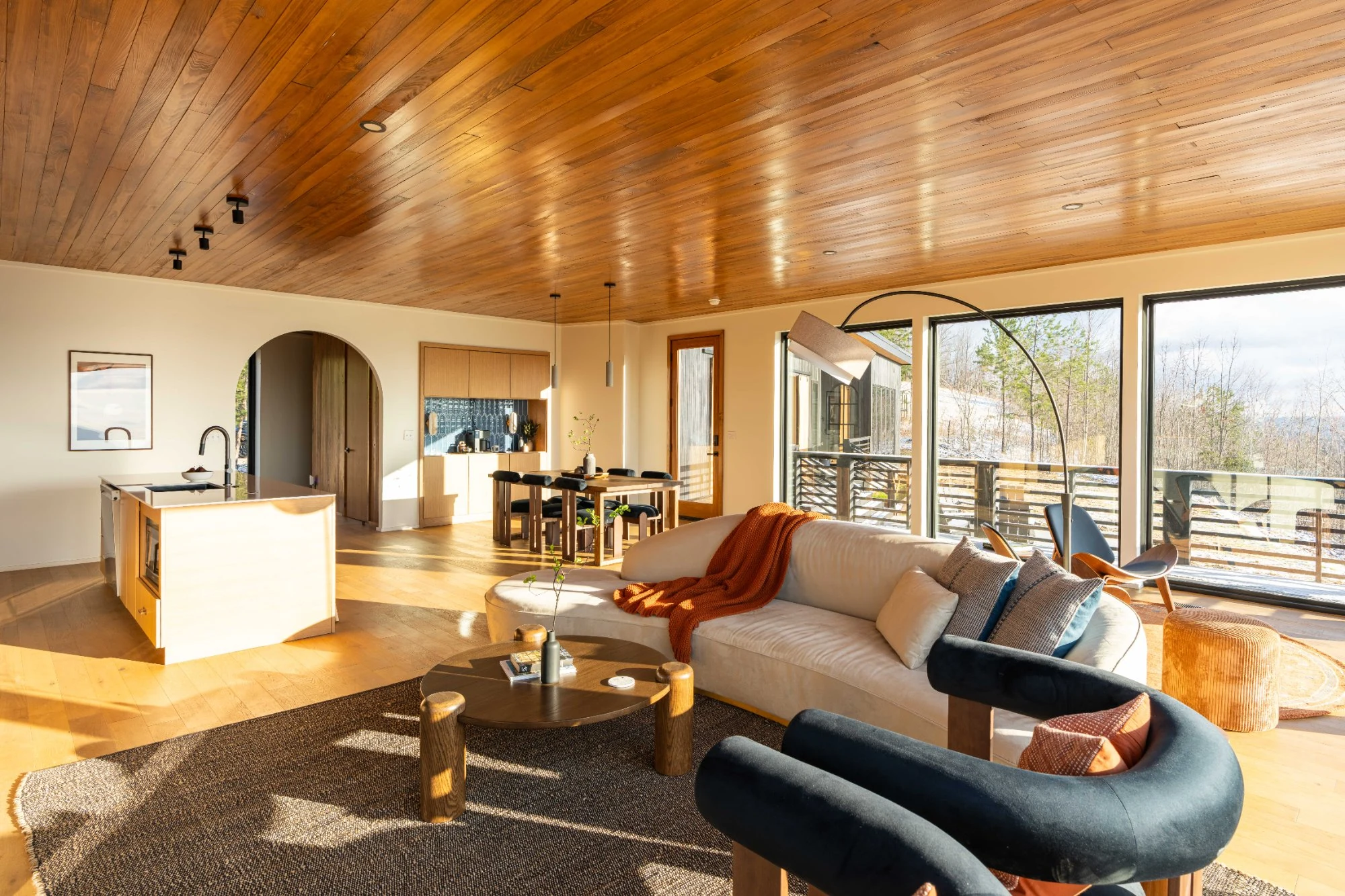 Midcentury-influenced living room with wood-plank ceilings and panoramic valley windows at Jackson Point