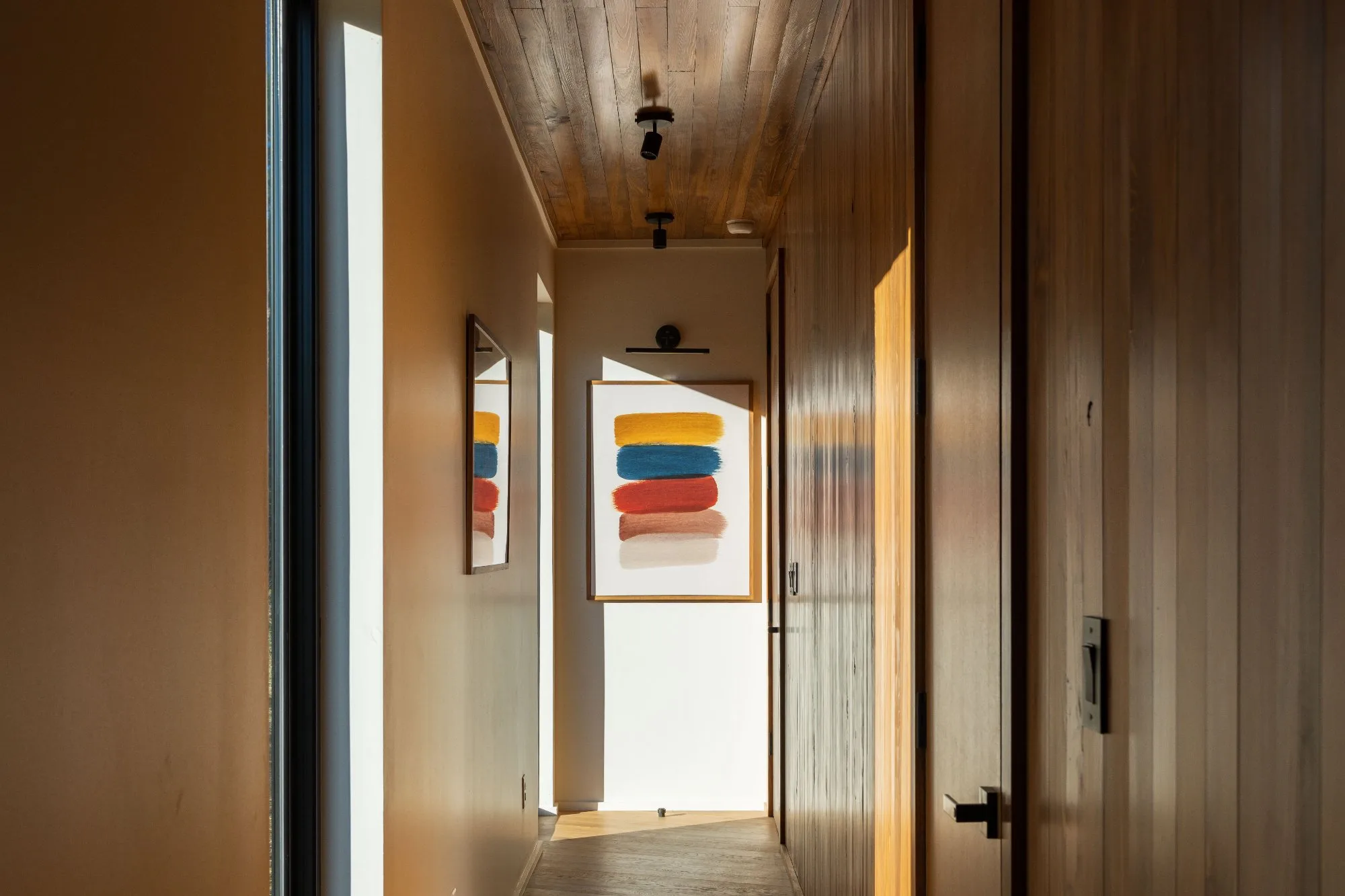 Hallway with abstract art and reclaimed wood ceiling at Jackson Point modern cabin, Tennessee