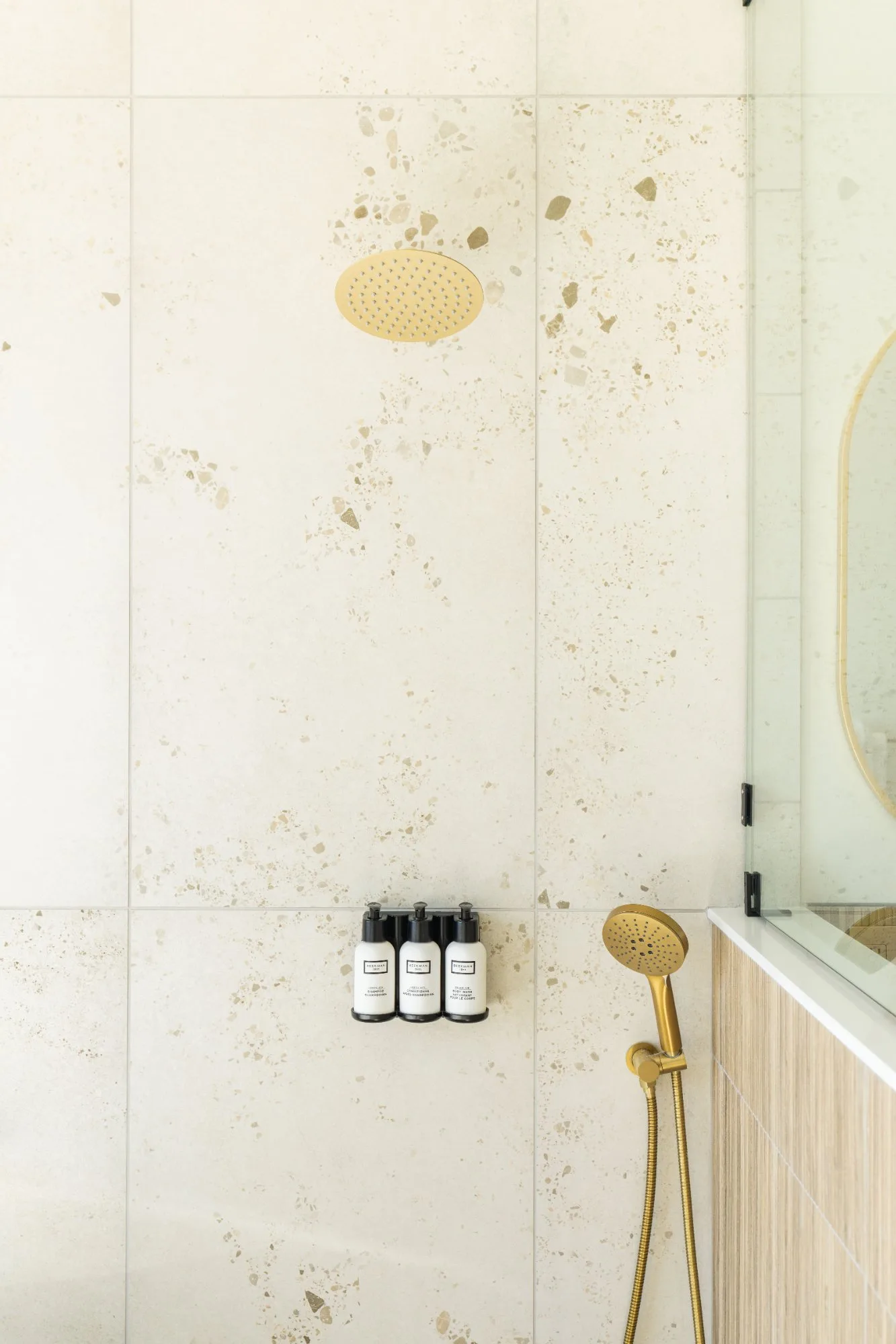 Terrazzo tile shower with gold rainfall head and fixtures at Jackson Point