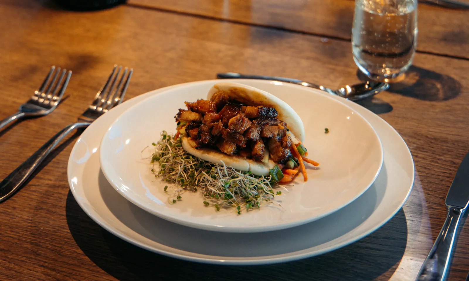 Private chef course of pork belly bao with microgreens, served with champagne at a Window Rock Modern dining table
